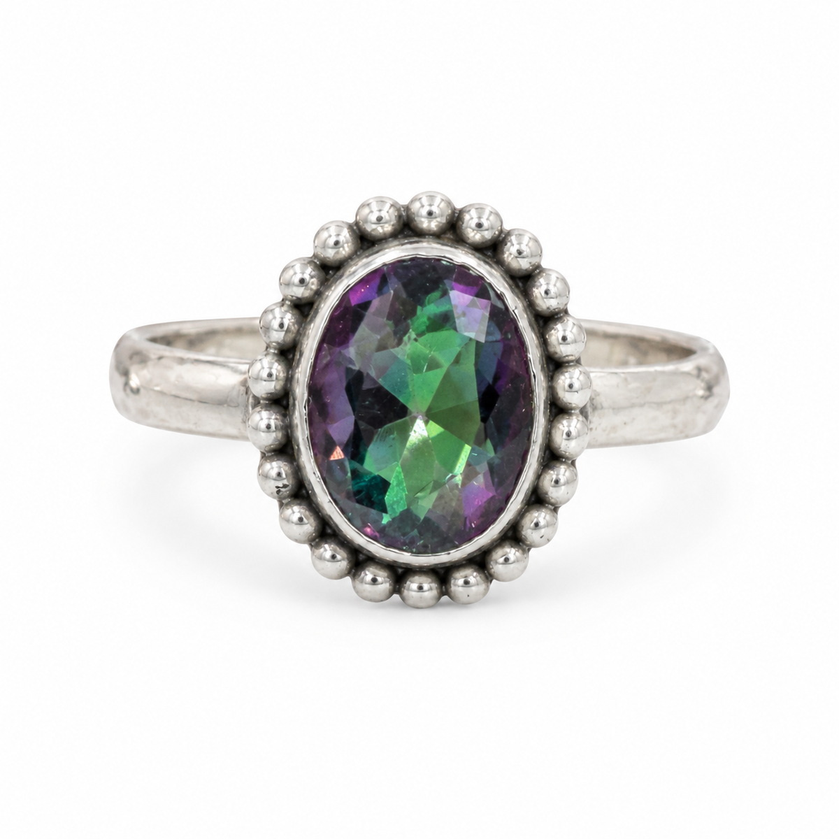 A sterling silver ring featuring an oval-cut iridescent gemstone with green, purple, and blue flashes, surrounded by a beaded halo and a textured silver band.